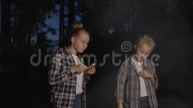 孩子们在森林徒步旅行中吃木棍上的<strong>棉花糖</strong>。 少女和少年吃<strong>棉花糖</strong>森林